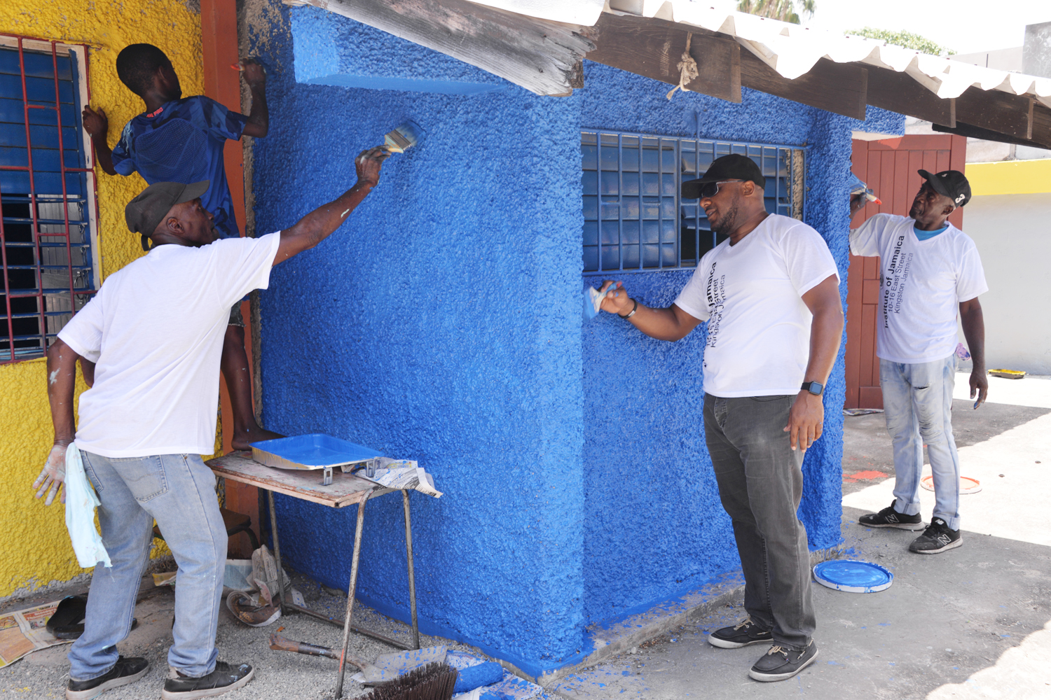 Executive Director, Institute of Jamaica, Leslie Harrow (second right), along with other volunteers, paints a section of the Highholborn Street Basic School on Labour Day, May 23.