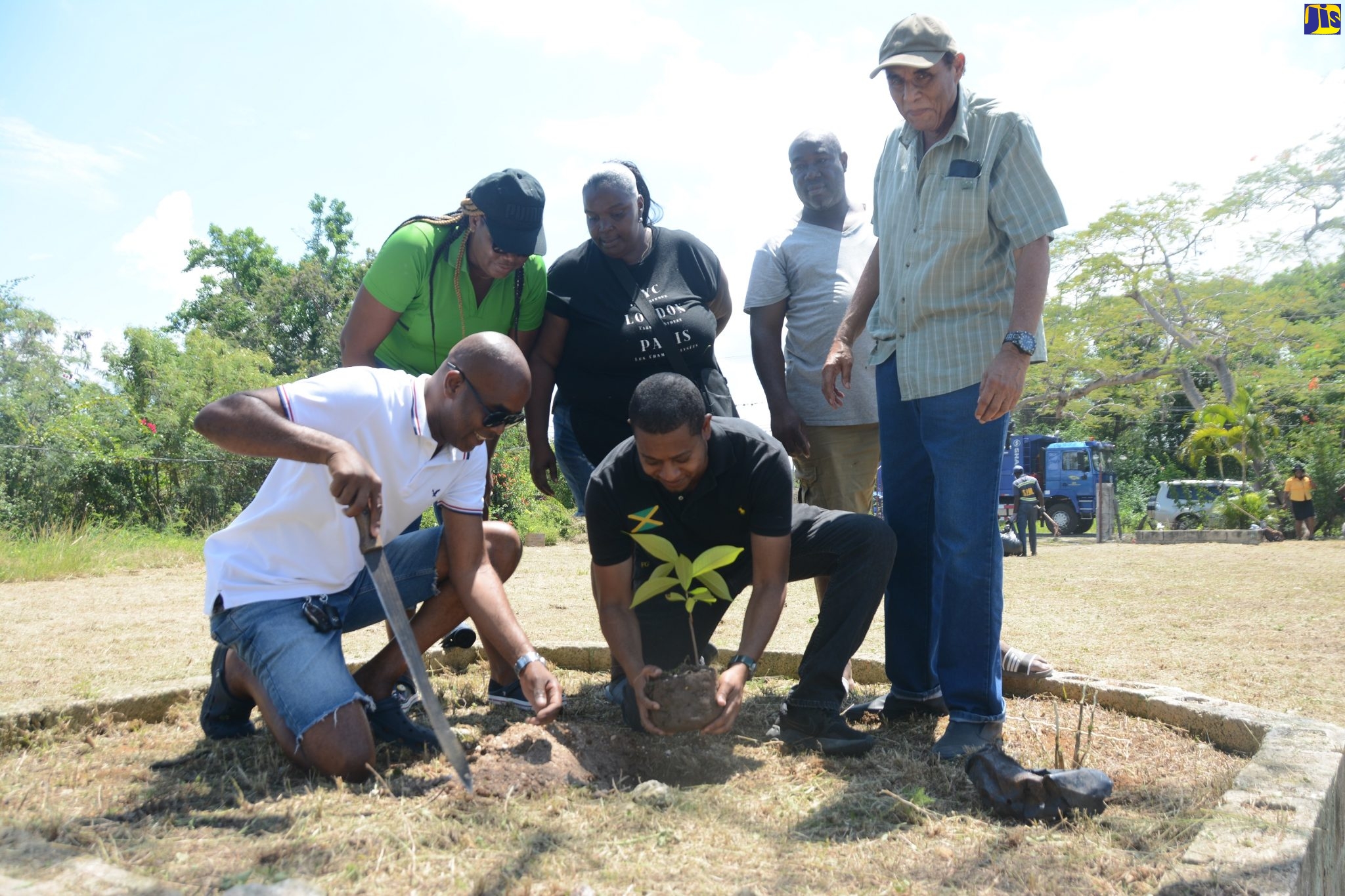Newly appointed Minister of Agriculture, Fisheries and Mining, and Member of Parliament for St. Elizabeth South Western, Hon. Floyd Green (front, centre), plants an apple seedling during the Labour Day parish project at Prosperity Park in the Parottee community on Tuesday, May 23. He is assisted by Regional Manager of SPM Waste Management Limited, Edward Muir (front, left). Looking on (from second left) are Labour Day Project Coordinator, Marcine Whitter; Assistant Secretary for the Parottee Citizens Association, Debbie Rosegreen; President of the Parottee Community Development Committee, Eric Samuels; and Mayor of Black River, Councillor Derrick Sangster.

