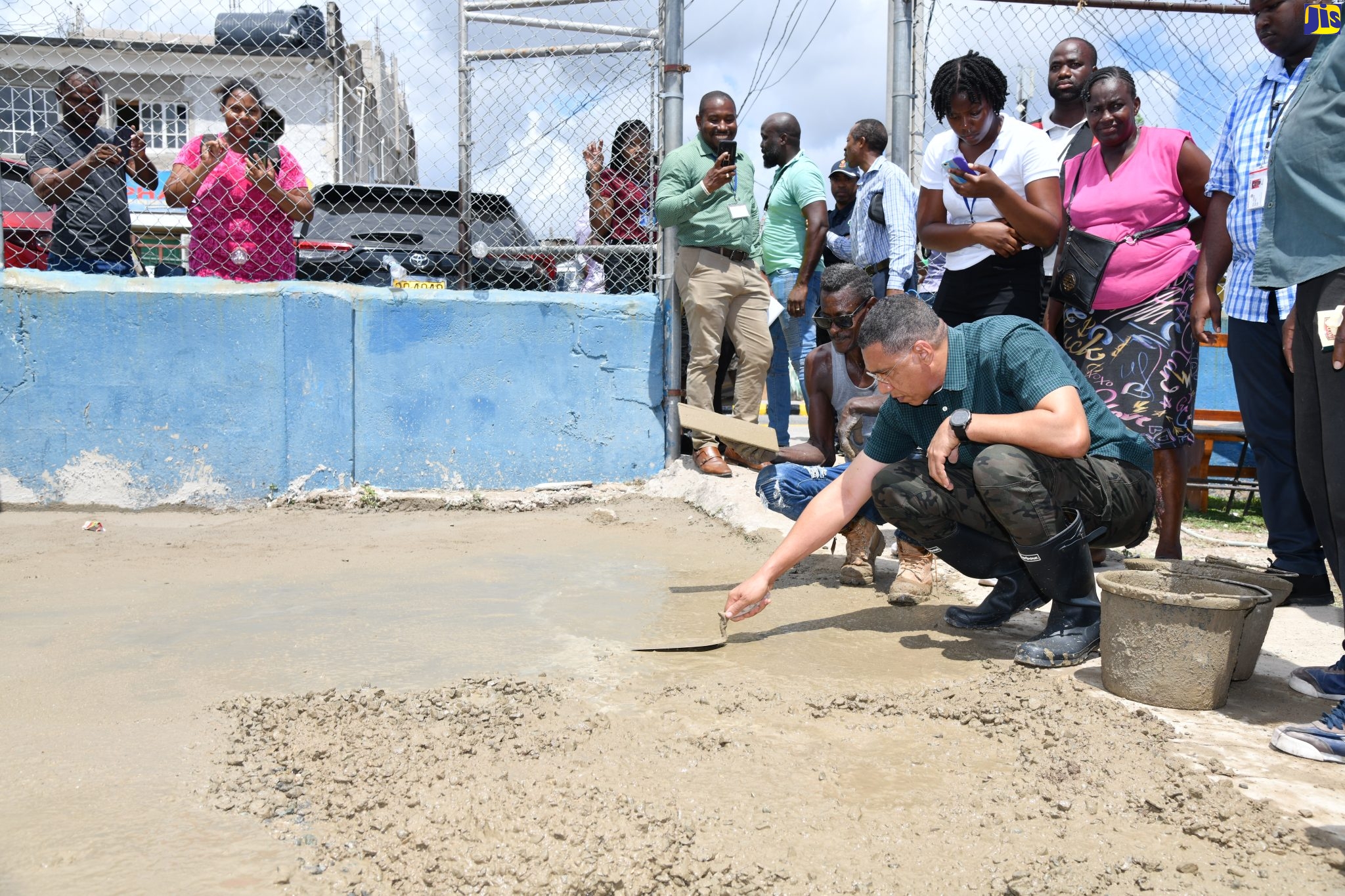 Prime Minister, the Most Hon. Andrew Holness (right, stooping), helps to pave the waiting area at the Olympic Gardens Health Centre in St. Andrew West Central, for which he is the member of Parliament, on Tuesday (May 23), as part of Labour Day activities in the constituency. Looking on are residents and volunteers of the community. 
