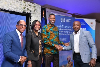 Minister of Labour and Social Security, Hon. Pearnel Charles Jr. (right), shakes hands with Director of the International Labour Organization (ILO) Decent Work Caribbean Team, Dr. Joni Musabayana (second from right), at the launch of the ‘Jamaica Just Transition: Embedding Climate Justice in Regional Policy Framework’ project at the Holiday Haven Condo Resort in St. Ann on Wednesday (November 27). Sharing the moment (from left) are Minister of State in the Ministry, Dr. the Hon. Norman Dunn; and Permanent Secretary (Acting), Dione Jennings. The launch took place during the Ministry’s Regional Labour Talk Roadshow.