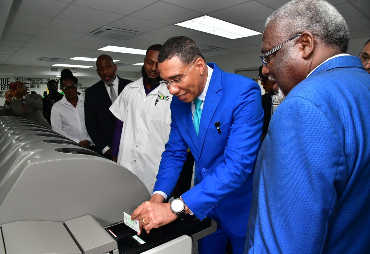 Prime Minister, Dr. the Most. Hon. Andrew Holness (second right), removes his newly printed National Identification (ID) Card from a machine located at the National Identification Registration Authority (NIRA) Personalisation Centre, at Central Sorting Office in Kingston, in November last year. Looking on (from left) are Executive Director of the Jamaica Council for Persons with Disabilities (JCPD), Dr. Christine Hendricks; Director General of the Planning Institute of Jamaica (PIOJ), Dr. Wayne Henry; Card Machine Operator, Rog-Jae Seymour and Chairman of NIRA, Bishop Conrad Pitkin.