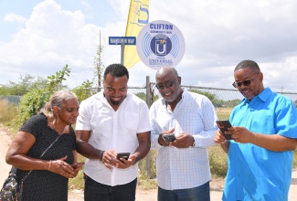 Managing Director of Universal Service Fund (USF), Charlton McFarlane (second left), uses his phone to access the Internet, following the launch of Community Wi-Fi in Clifton in Portmore, St. Catherine on Friday (February 7). He is joined by (from left), community member, Rosemarie McNaughty; Member of Parliament (MP) for St. Catherine Southern, Fitz Jackson; and Councillor for Greater Portmore North, Gary Nicholson.