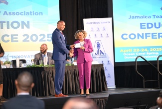 Minister of Education, Skills, Youth and Information, Senator Dr. the Hon. Dana Morris Dixon, accepts a donation form for a Critical Illness Trust Fund from President of the Jamaica Teachers' Association (JTA), Dr. Mark Smith, during day one (April 22) of a three-day JTA Education Conference 2025, being held at Ocean Coral Spring in Trelawny.