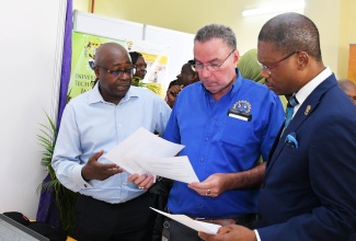 Science, Energy, Telecommunications and Transport Minister, Hon. Daryl Vaz (centre) peruses a document with University of Technology Jamaica (UTech) President, Dr. Kevin Brown (right), and Chief Category Manager, Hardware and Lumber Limited, Patrick Chambers. The event was the UTech Jamaica’s Research, Technology and Innovation Day held on Thursday (April 10) at the institution’s Old Hope Road location.
