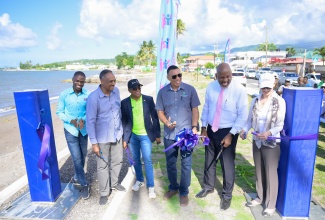 Prime Minister, Dr. the Most Hon. Andrew Holness (third right) leads a ribbon cutting exercise for the Annotto Bay Coastal Protection Project in St. Mary on May 16. He is joined by, from left, Project Manager at the Jamaica Social Investment Fund (JSIF), Dane Mclean; JSIF Managing Director, Omar Sweeney; Member of Parliament for South east St. Mary, Dr. the Hon. Norman Dunn; JSIF Chairman, Dr. Wayne Henry; and Country Director for the Caribbean, World Bank Group, Lilia Burunciuc.