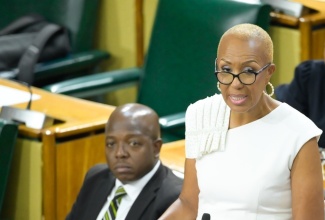 Minister of Finance and the Public Service, Hon. Fayval Williams, speaking in the House of Representatives. Listening is Minister of Labour and Social Security, Hon. Pearnel Charles Jr.