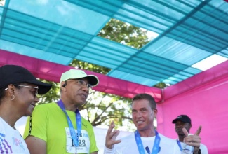 Prime Minister, Dr. the Most Hon. Andrew Holness (centre), listens to a point being made by Sandals Resorts International Executive Chairman, Adam Stewart (right), at the Jill Stewart MoBay City Run at the Harmony Beach Park, Montego Bay, St. James, on May 4. Looking on (left) is Minister of Legal and Constitutional Affairs, Hon. Marlene Malahoo Forte.

