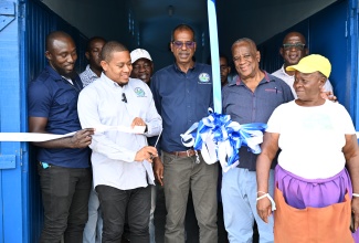 Minister of Agriculture, Fisheries and Mining, Hon. Floyd Green (second left), cuts the ribbon to mark the official opening of the $3-million gear shed and bathroom facilities at the Black River Fishing Beach in St. Elizabeth, on Wednesday, June 18.  He is  joined by State Minister in the Ministry, Hon. Franklin Witter (second right); Chief Executive Officer (CEO) of the National Fisheries Authority (NFA), Dr. Gavin Bellamy (centre), vendors and other stakeholders. 