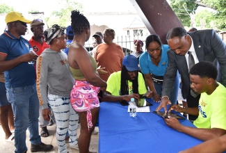 Managing Director of Jamaica Social Investment Fund (JSIF), Omar Sweeney (standing, second right), and members of the Jamaica Public Service (JPS) team, assist residents to get registered during a Community Electrification Fair held at the Jones Town Baptist Church in Kingston on Wednesday (June 11). The JPS personnel (from left) are Assistant Control Engineer, Ronald Gazel; Community Relations Officer, Kerrica McGregor and intern, Jordan McConnel. The islandwide fairs are aimed at registering vulnerable households to benefit from domestic house wiring under the Community Electrification Project being undertaken by the Jamaica Social Investment Fund (JSIF) in partnership with JPS. 