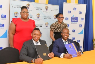 Acting President of the National Water Commission (NWC), Kevin Kerr ((left), and President of the University of Technology (UTech) Jamaica, Dr. Kevin Brown, celebrate the signing of an agreement to facilitate the training of persons in Non-Revenue Water (NRW) detection and mitigation, on June 11, at the Papine campus of the University, in Kingston. Standing are Senior Legal Officer at the NWC, Shanique Leon (left), and Registrar at Utech Jamaica, Marion Brown.

