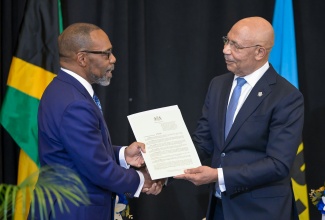 Governor-General, His Excellency the Most Hon. Sir Patrick Allen (right), presents newly installed President of the Caribbean Court of Justice (CCJ), Hon. Mr. Justice Winston Anderson, with the Proclamation of his appointment during Sunday’s (July 6) swearing-in ceremony at the Jewel Grande Resort in Montego Bay, St. James.


