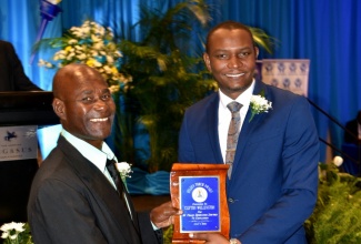 Jamaica Teachers’ Association (JTA) President, Dr. Mark Smith (right), presents Clifton Wellington with the JTA’s Golden Torch Award in recognition of his 41 years of dedicated service to education, during the recent presentation ceremony at The Jamaica Pegasus hotel in New Kingston.