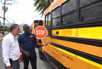 Minister of Science, Energy, Telecommunications and Transport, Hon. Daryl Vaz (left), listens as Jamaica Urban Transit Company (JUTC) contracted engineer, Barrington Brown, highlights the features of one of the buses that will be utilised in the rural school bus system, following a press conference on Tuesday (July 8),  at the Petroleum Corporation of Jamaica (PCJ) Auditorium in Kingston.

