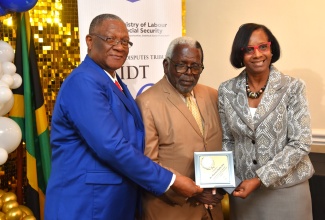 Acting Permanent Secretary in the Ministry of Labour and Social Security, Dione Jennings and Chairman of the Industrial Disputes Tribunal (IDT), Errol Miller (left), present an award to former Labour Minister, Pearnel Charles Sr., in recognition of his pivotal role in the 2010 amendment of the Labour Relations and Industrial Disputes Act (LRIDA). The presentation was made during the IDT’s 50th Anniversary Luncheon and Awards Ceremony held on Friday (July 11), at the Courtleigh Hotel and Suites in New Kingston.