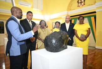 Governor-General, His Excellency the Most Hon. Sir Patrick Allen (second right), and Prime Minister, Dr. the Most Hon. Andrew Holness (second left), listen as Chief Curator at the National Gallery of Jamaica, O’Neil Lawrence (left), provides an overview of one of the pieces displayed during an exhibition coinciding with the Governor General’s reception to celebrate Jamaica’s 63rd Anniversary of Independence. Also listening are (from third left): Minister of Culture, Gender, Entertainment and Sport, Hon. Olivia Grange; Her Excellency, the Most Hon. Lady Allen; and Member of Parliament for St. Andrew South Western, Dr. Angela Brown Burke. The reception was held at King’s House on Thursday (July 24).