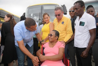 Prime Minister, Dr. the Most Hon. Andrew Holness (left) converses with Jodi-Ann Baker (seated, centre), a commuter with special needs, during the handover of 93 buses to the Jamaica Urban Transit Company (JUTC) at the Portmore JUTC bus depo in Braeton, St. Catherine, on Wednesday (July 16). They are joined by Member of Parliament for Portland Eastern, Ann-Marie Vaz; Minister of Science, Energy, Telecommunications and Transport, Hon. Daryl Vaz; State Minister in the Ministry of Foreign Affairs and Foreign Trade and Member of Parliament for East Central St. Catherine, Hon. Alando Terrelonge; and Golden Age Home nurse aide, Everton Watt.

