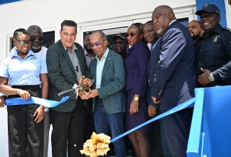 Deputy Prime Minister and Minister of National Security, Hon. Dr. Horace Chang (fourth left), is assisted by Minister of State in the Office of the Prime Minister and Member of Parliament for St. James Southern, Hon. Homer Davis (third left), in cutting the ribbon to officially open the newly built state-of-the-art Anchovy Police Station in St. James, on Tuesday (August 5). Looking on (from left) are Minister of State in the Ministry of National Security, Hon. Juliet Cuthbert Flynn; Custos Rotulorum for St. James, Bishop Conrad Pitkin; and other stakeholders.