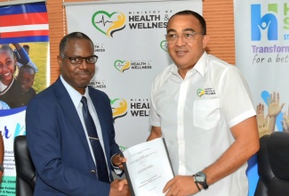 Minister of Health and Wellness, Dr. the Hon. Christopher Tufton (right), and Director of the Epidemiology Research Unit (ERU) at the University of the West Indies (UWI), Professor Trevor Ferguson, shake hands while displaying the contract for the fourth Jamaica Health and Lifestyle Survey (JHLS IV), during the recent signing ceremony at the Ministry’s New Kingston offices.