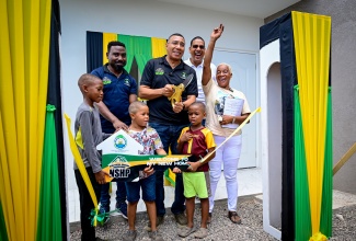 Prime Minister, Dr. the Most Hon. Andrew Holness (centre), cuts the ribbon for a new three-bedroom home being handed over to a joyful Paulette Reynolds (right), in Central Kingston on Thursday (August 7). Sharing the moment are Senior Director in the Ministry of Economic Growth and Job Creation, Richard Cargill (left); Member of Parliament (MP) for Kingston Central, Donovan Williams (right) and Ms. Reynolds’ grandchildren (from left), Kardel, Aaron and Rodel. The home was provided to the family under the New Social Housing Programme (NSHP).

