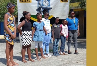 Member of the Old Harbour and Friends Association (OHFA), Loris Foreman (right), shares a photo opportunity with some of the students who received donation of school supplies, scholarships and cash grants, during a recent outreach event held at the Old Harbour Primary School in St. Catherine.


